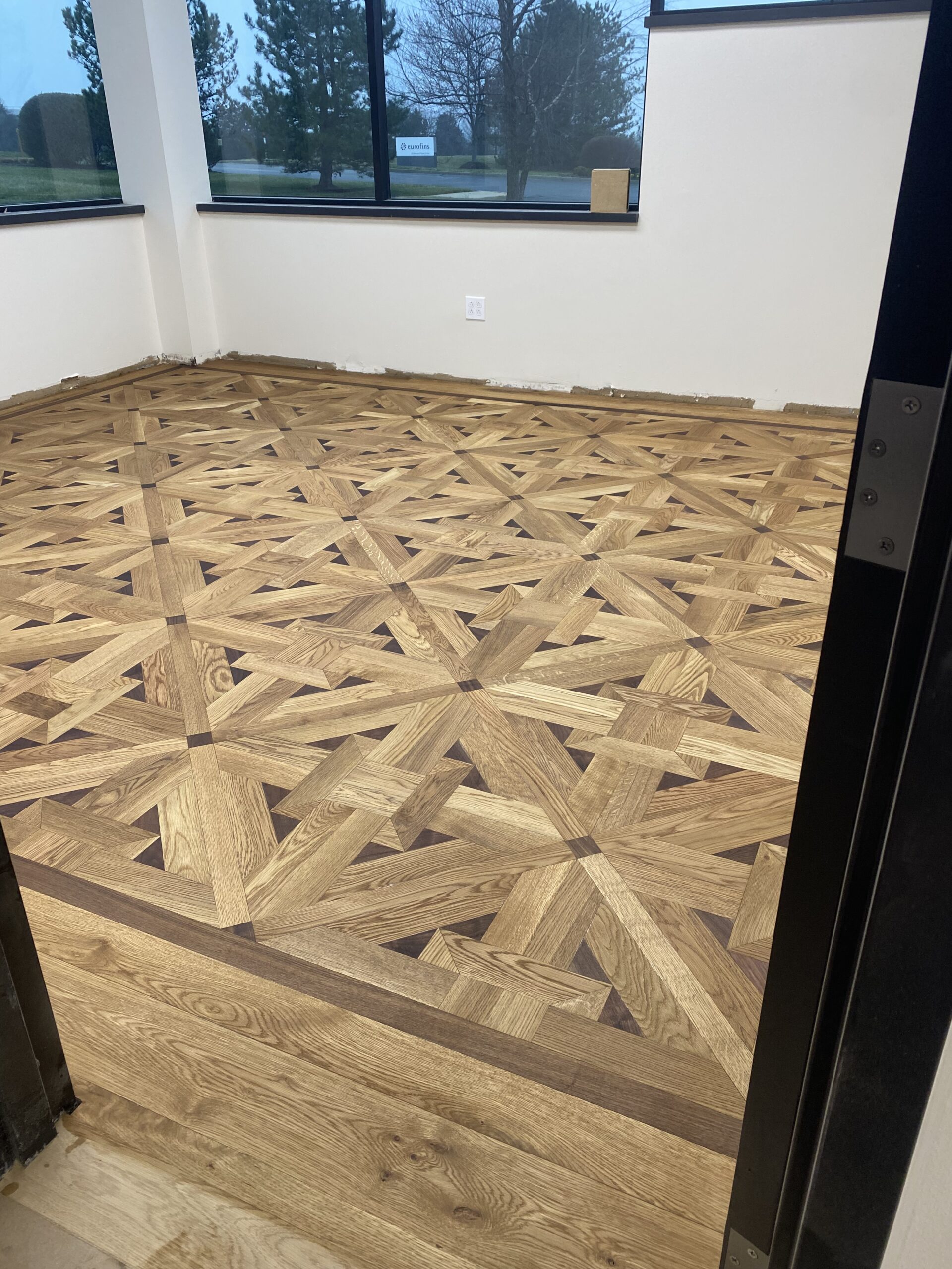 Restored hardwood floor with a circular red and black custom inlay
